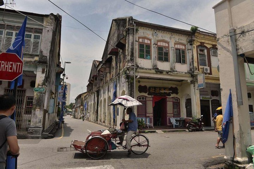 A street scene with a man riding a bicycle with a cart, buildings with signs, and a stop sign. 4