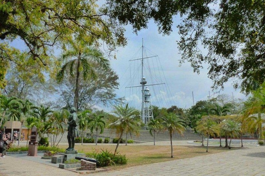 A statue of a man, a ship, and palm trees in a park. 3