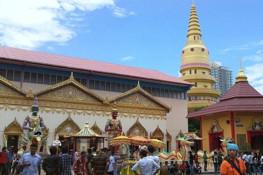 A temple with ornate architecture, a large golden stupa, and a crowd of people. 2