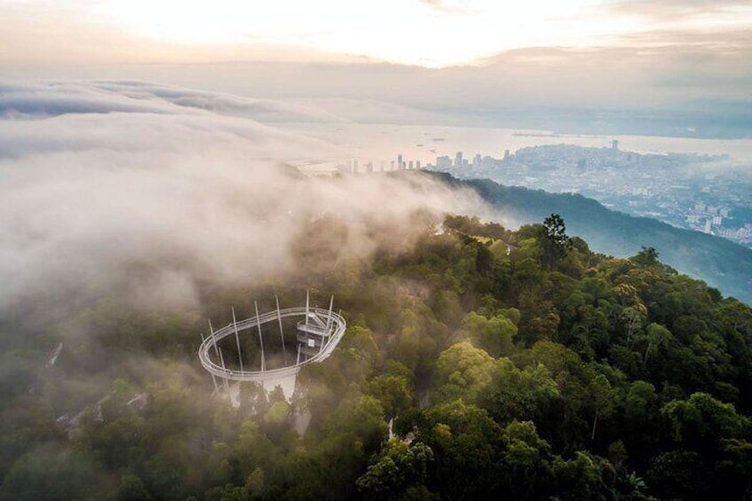 A stadium surrounded by a forested mountain range with a city skyline in the distance. 1