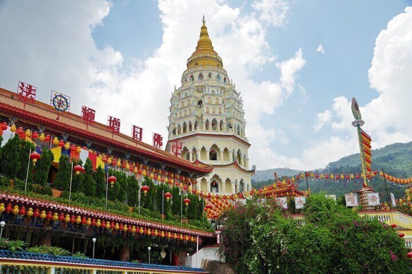 A large white temple with a golden spire, surrounded by colorful decorations and greenery. 4