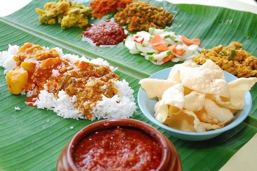 A variety of Indian dishes on a banana leaf, including rice, curry, and snacks. 1