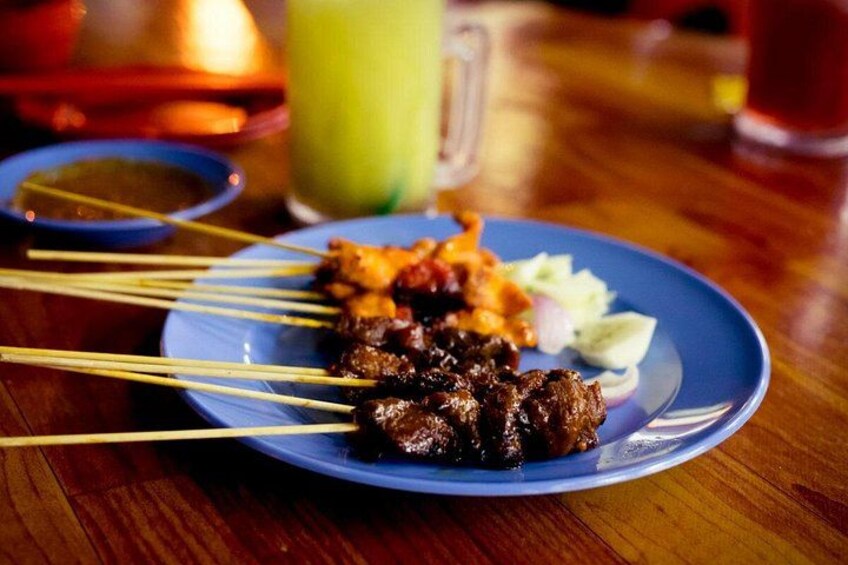 A plate of skewered meat with vegetables and a green drink in the background. 3