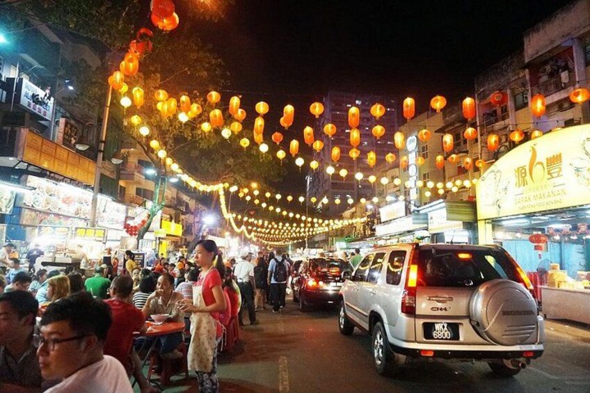 A street at night with lanterns, vehicles, and people. 4