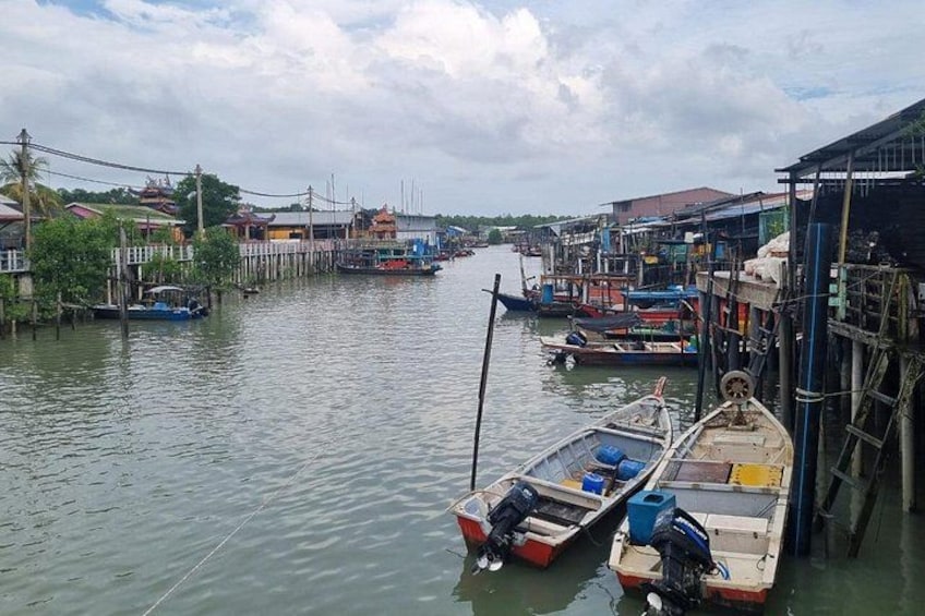 A calm river with boats docked at wooden piers, surrounded by traditional buildings. 3
