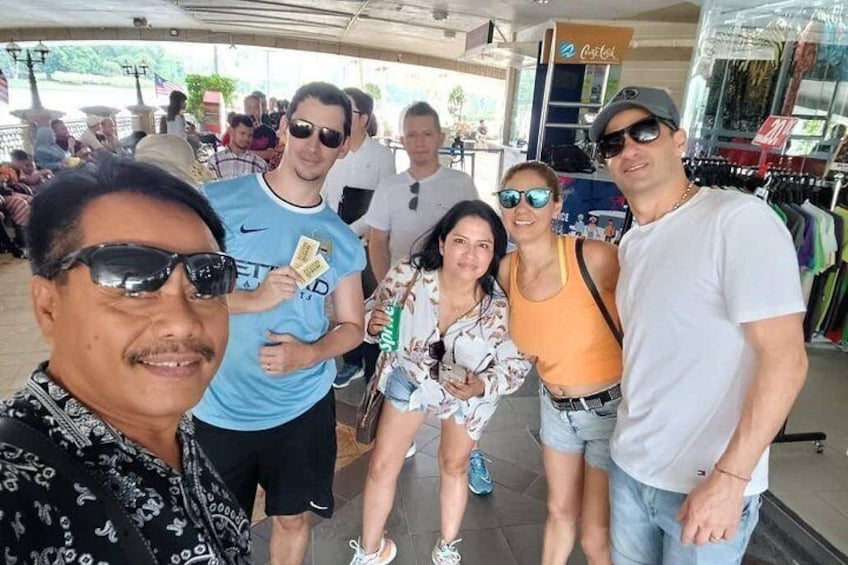 Un groupe de personnes posant pour une photo dans un cadre extérieur, avec un magasin en arrière-plan. 1
