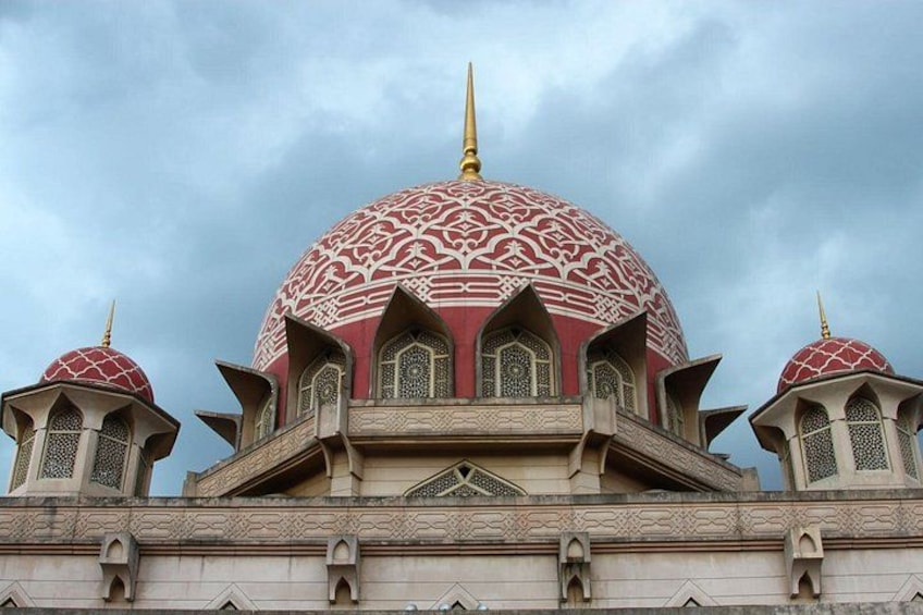 Une mosquée dotée d’un grand dôme central et de deux dômes plus petits, ornée de motifs complexes et surmontée d’un haut minaret. 5
