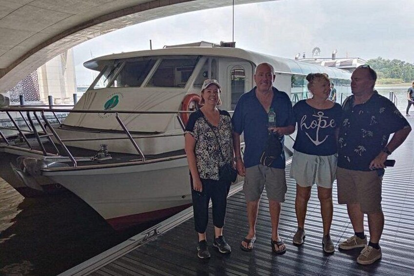 A group of people standing on a dock with a boat in the background. 3