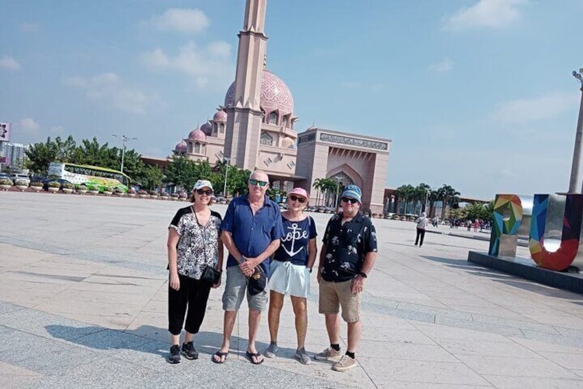 A group of people standing in a plaza with a large building and a colorful sculpture in the background. 4