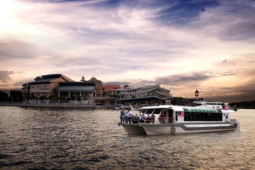 A boat with passengers, a waterfront building, and a sunset sky. 4