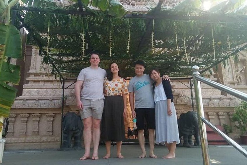 A group of people standing in front of a temple with a stone structure and a metal railing. 4