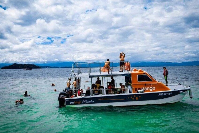 A boat named 'seaango' with people on board and swimmers in the water. 4