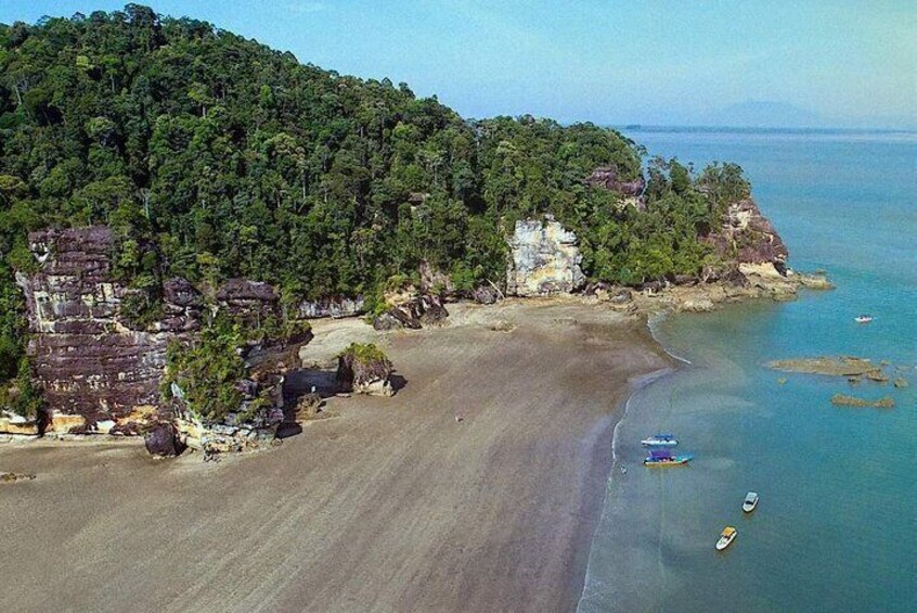 A beach with boats, a forested hill, and buildings. 3