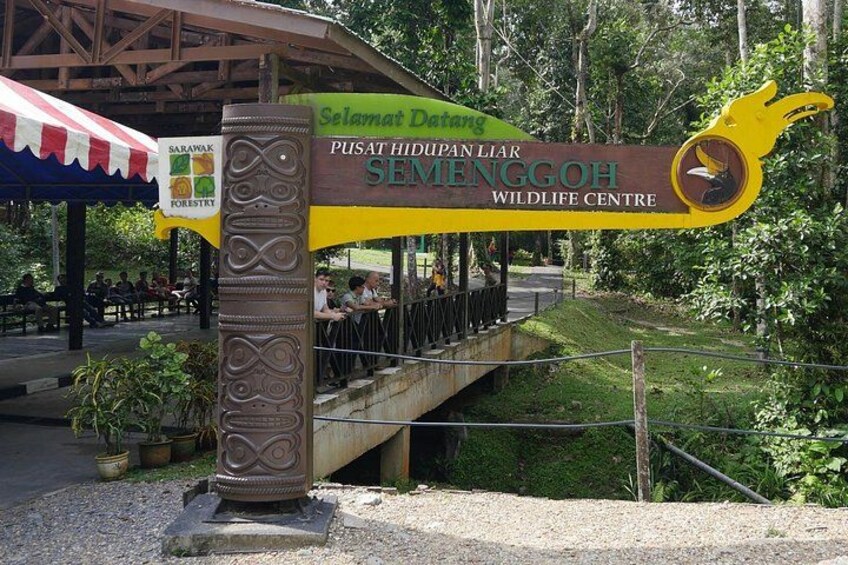 A wildlife center sign with a bridge and a forested area. 2