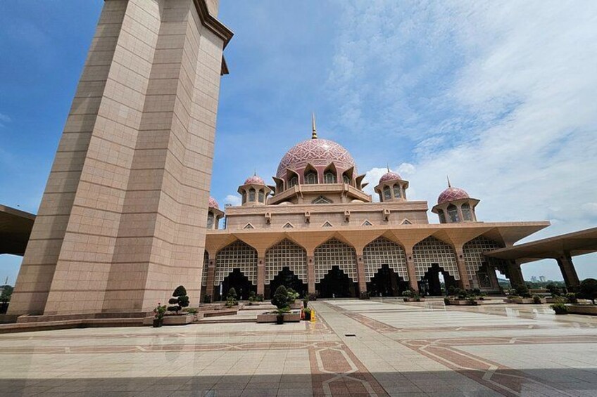 A large mosque with multiple domes and minarets, a tall minaret, and a spacious courtyard with tiled patterns. 2