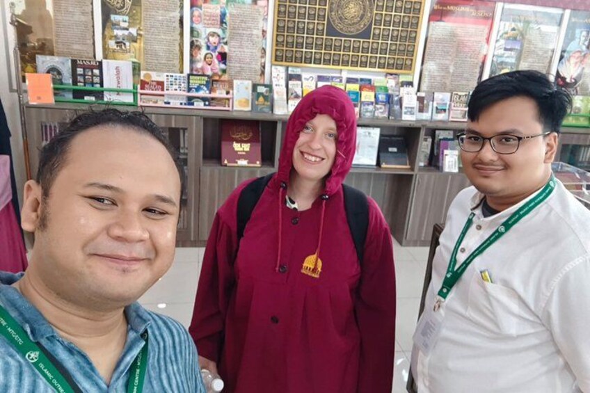 Three people standing in a bookstore with bookshelves and informational displays in the background. 2