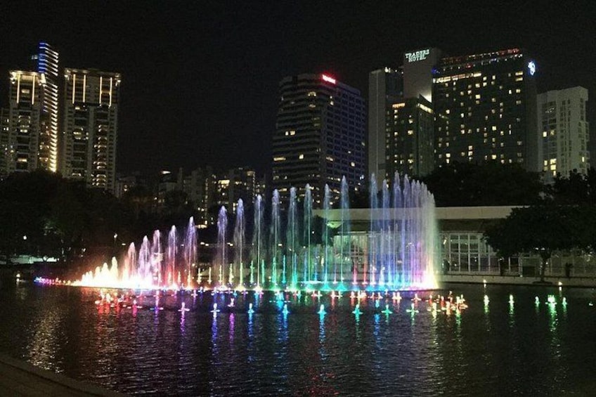 A nighttime cityscape with a colorful fountain display reflecting on the water. 2