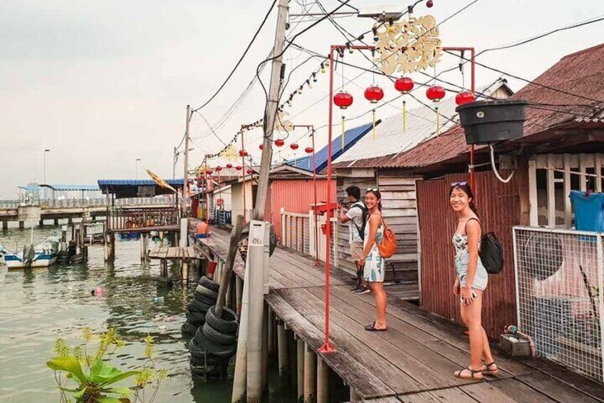 A wooden dock with people standing on it, a waterway with boats, and a traditional building with red lanterns. 2