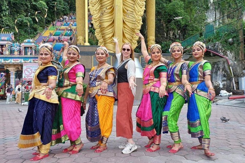A group of women in colorful traditional attire standing in front of a large golden statue. 1