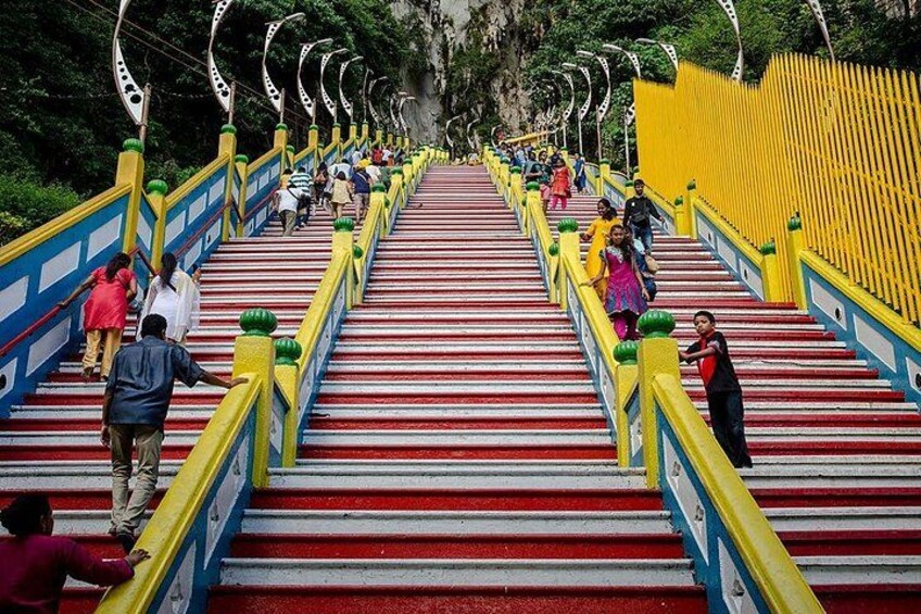 A staircase with red steps and yellow railings, surrounded by greenery. 4