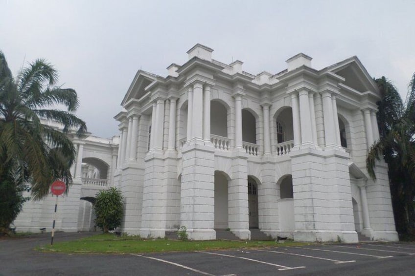 A large white colonial-style building with multiple arches and columns, surrounded by palm trees. 2