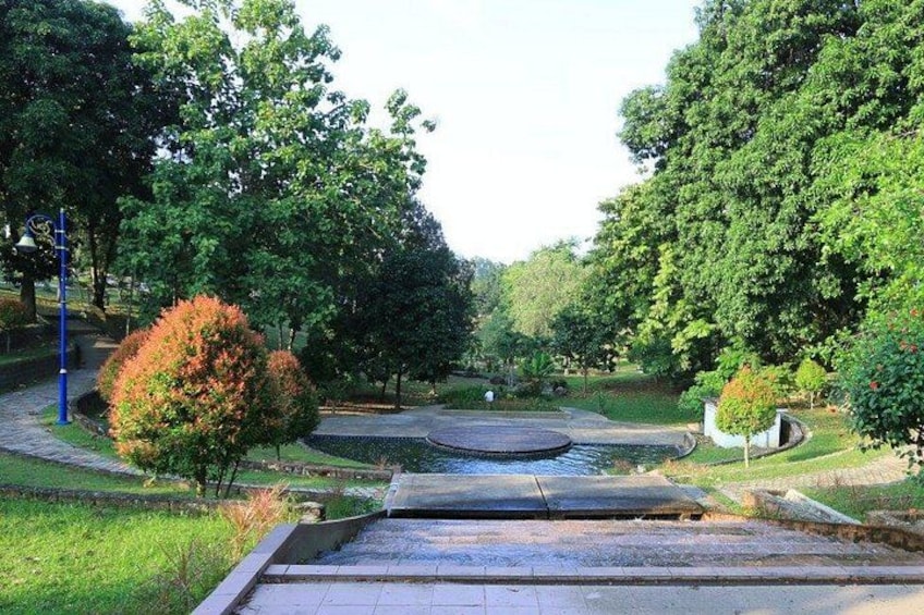 A park with a pond, trees, and a pathway. 5
