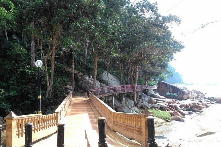 A wooden bridge with railings, surrounded by trees and rocks, leading to a beach. 3