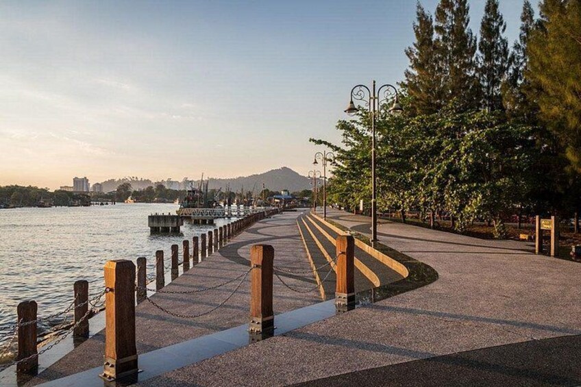 A waterfront promenade with wooden posts, a paved walkway, and a row of trees. 4