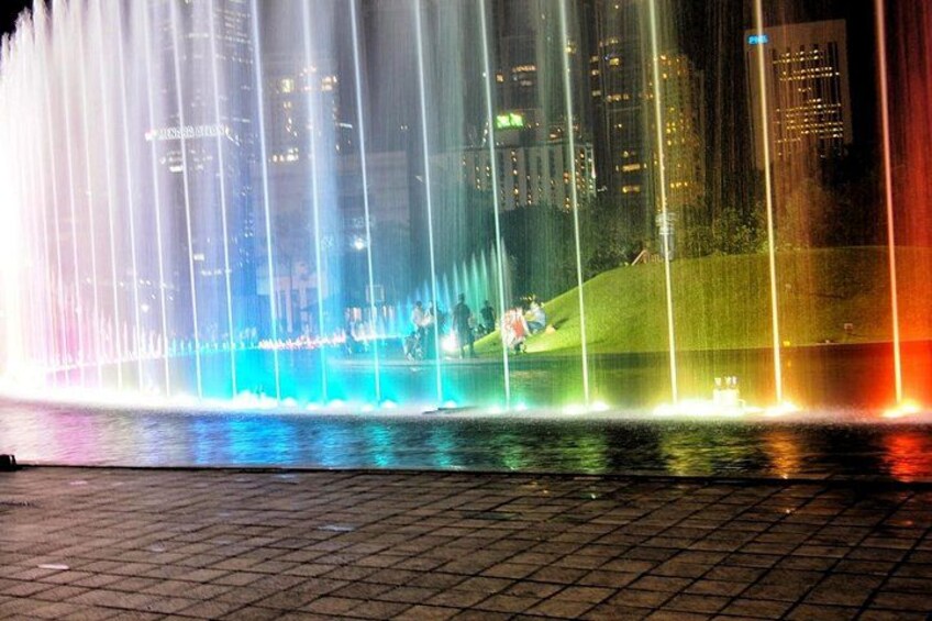 A nighttime cityscape with a brightly lit fountain. 2