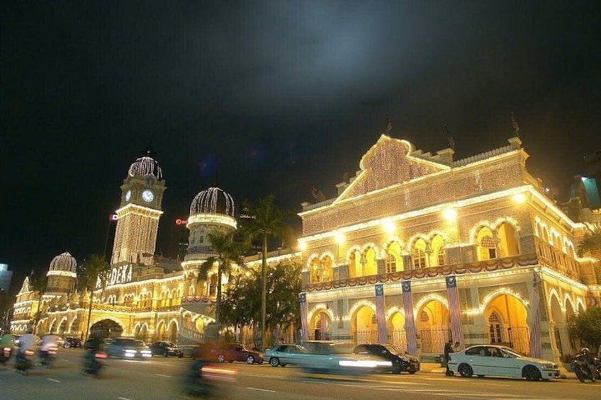 A brightly lit historic building with domes and a clock tower at night. 3