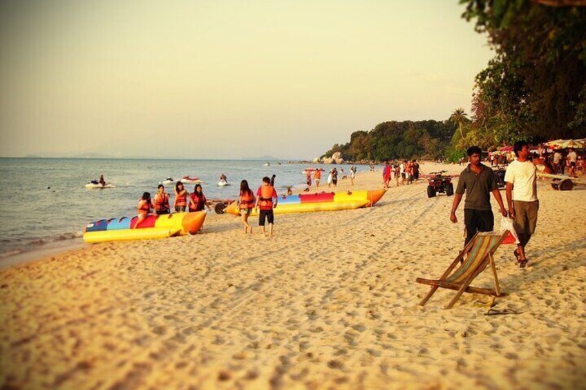 A beach with people, inflatable boats, and a wooden chair. 5