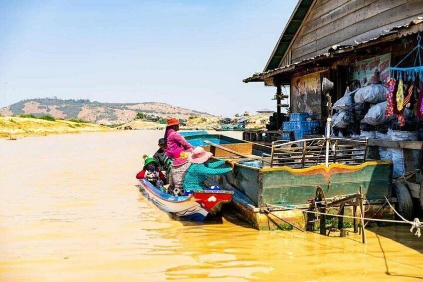 A boat docked at a wooden structure with people on board, surrounded by water and hills in the background. 5