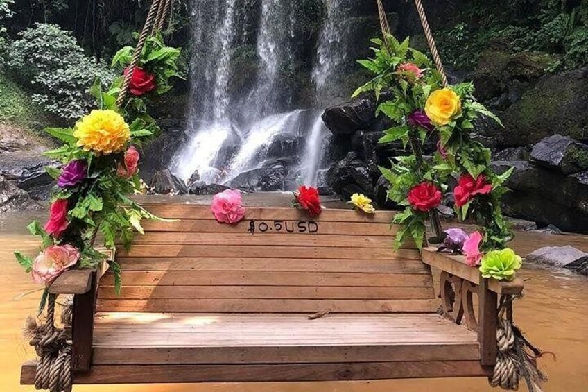 Una plataforma de madera con una cascada de fondo, decorada con flores de colores. 1