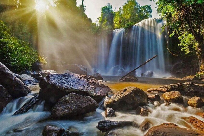 Una cascada rodeada de rocas y follaje. 4