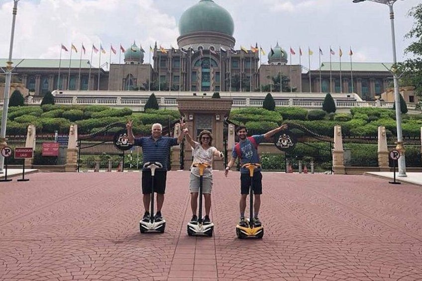 Three people on hoverboards in front of a large building with flags. 2