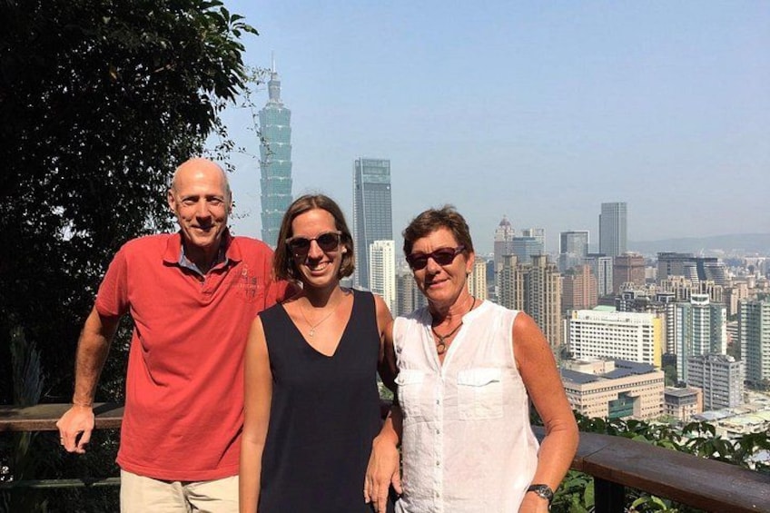 Drie personen staan op de achtergrond van een stadsgezicht. 2