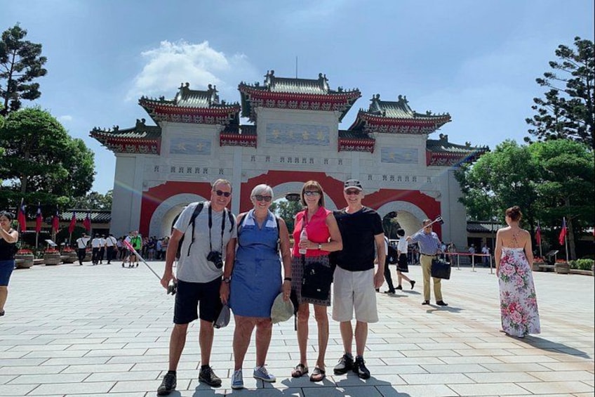 Een groep mensen poseert voor een traditioneel Chinees poort met gedetailleerde architectuur. 3
