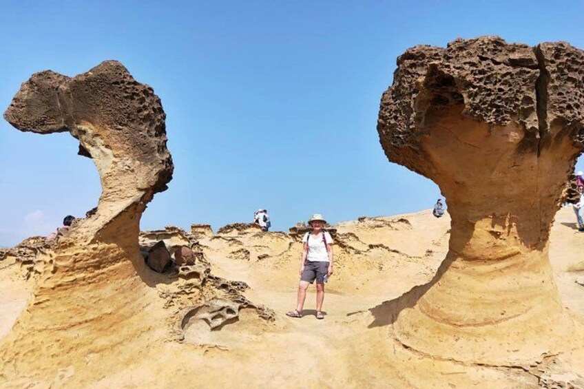 A person standing between two rock formations with a clear sky in the background. 2