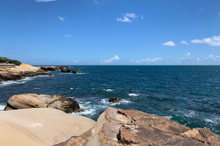 A rocky coastline with waves crashing against the rocks under a clear blue sky. 2