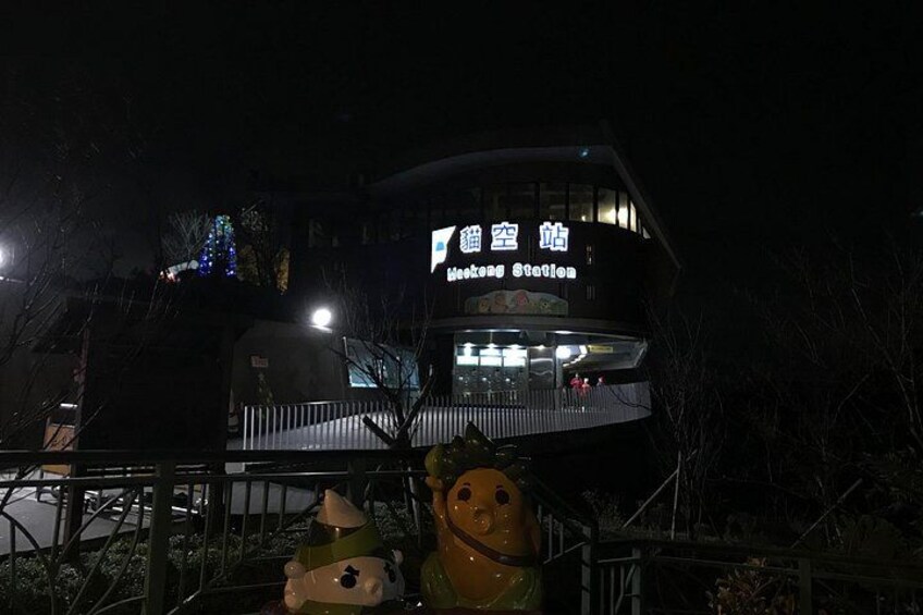 A building with illuminated signage, a fenced area, and two large animal statues. 3
