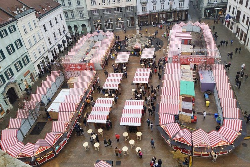 A crowded square with red and white striped canopies and tables, surrounded by historic buildings. 1
