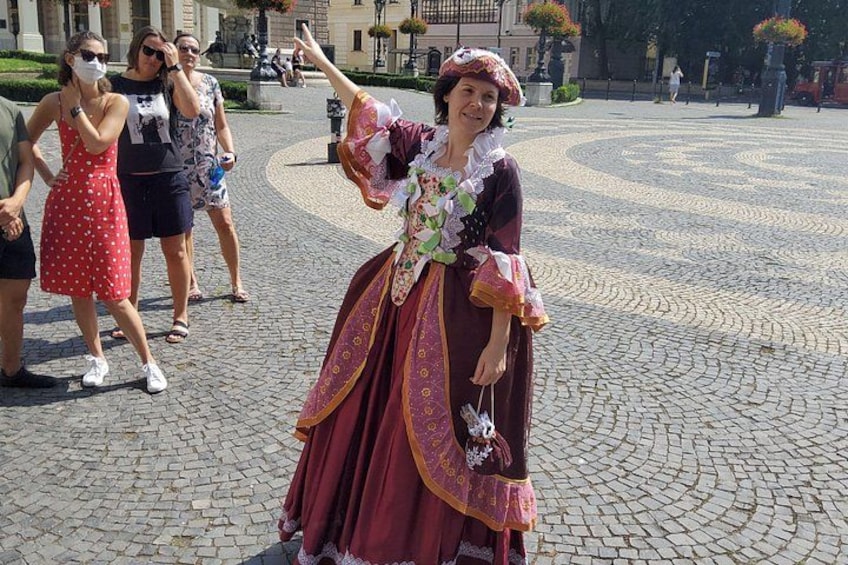 A person in historical costume, a cobblestone plaza, and other people in modern attire. 2