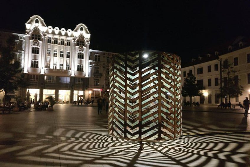 A modern sculpture in a plaza at night, with shadows cast on the ground. 5