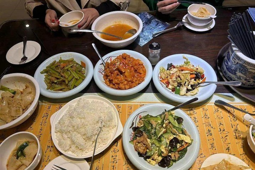 A table with various dishes including rice, vegetables, and a soup. 2