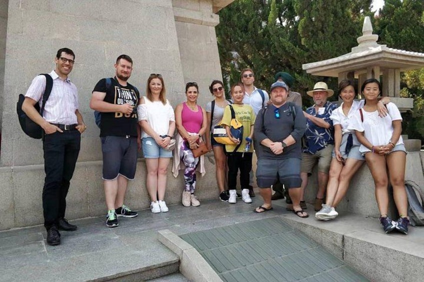 A group of people standing on steps in front of a stone structure with a fountain. 1