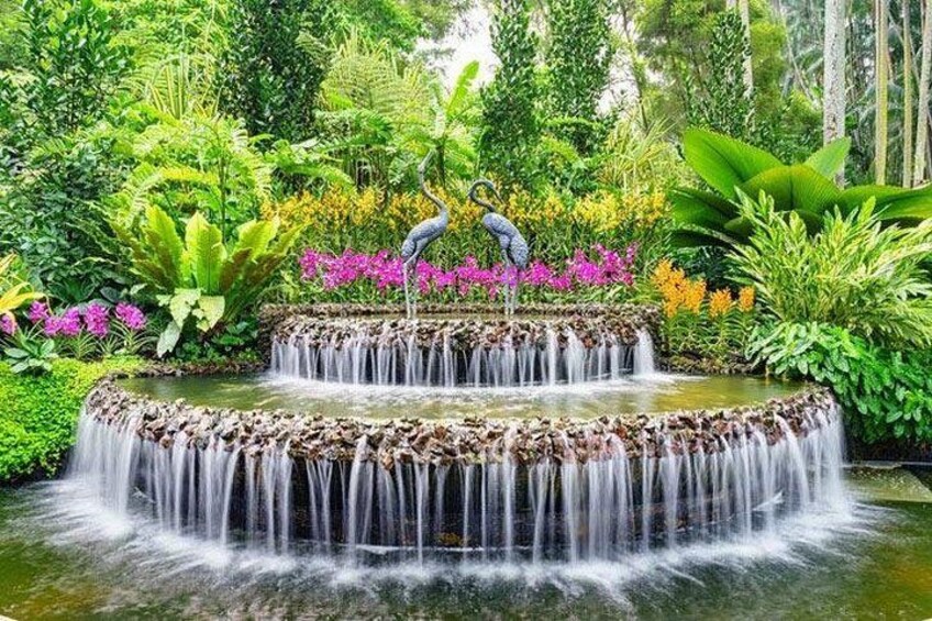 Una cascada con varios niveles rodeada de exuberante vegetación y flores coloridas. 1