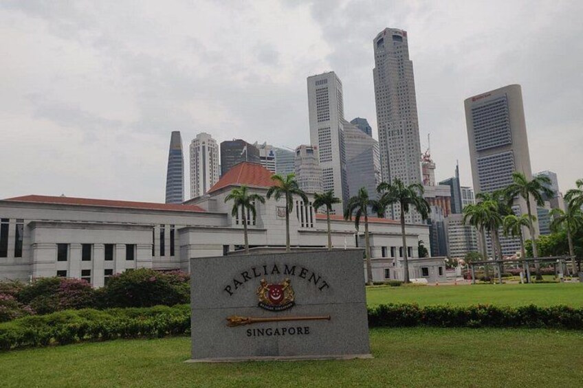 Un letrero con la palabra 'Parliament' y 'Singapore', con un paisaje urbano de fondo. 5