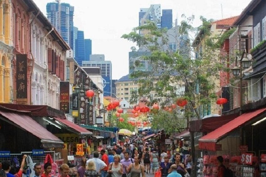 Una calle concurrida con edificios tradicionales, faroles rojos y gente caminando. 3