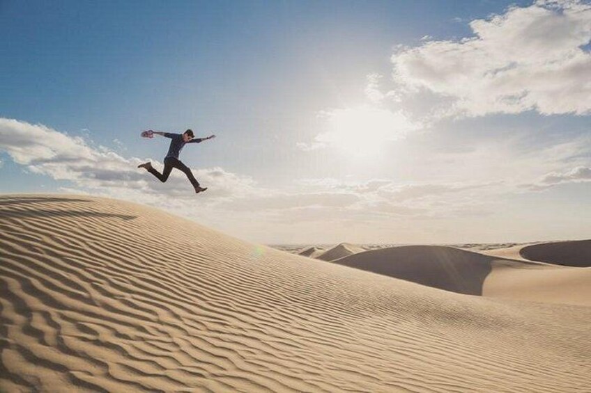 Iemand springt over duinen in een woestijnlandschap. 3