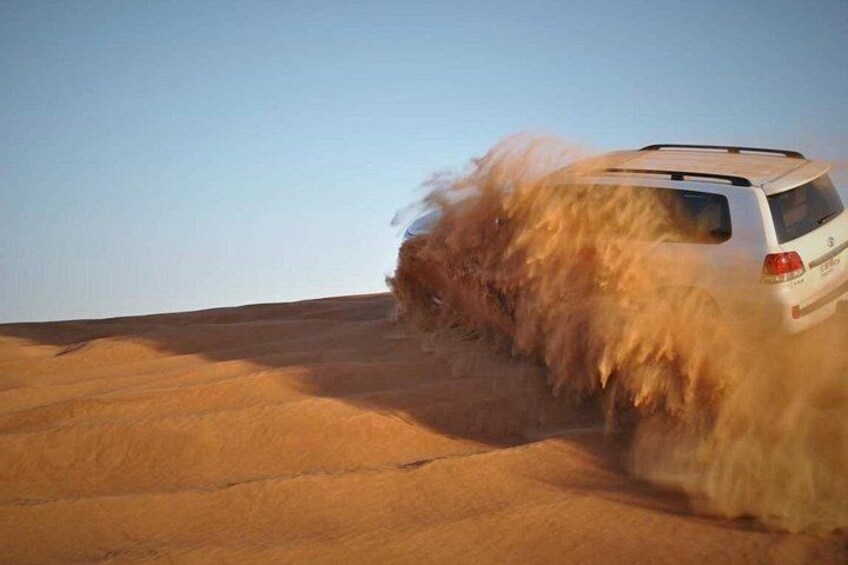 Un VUS blanc roule dans un désert, et le véhicule soulève des nuages de sable. 4